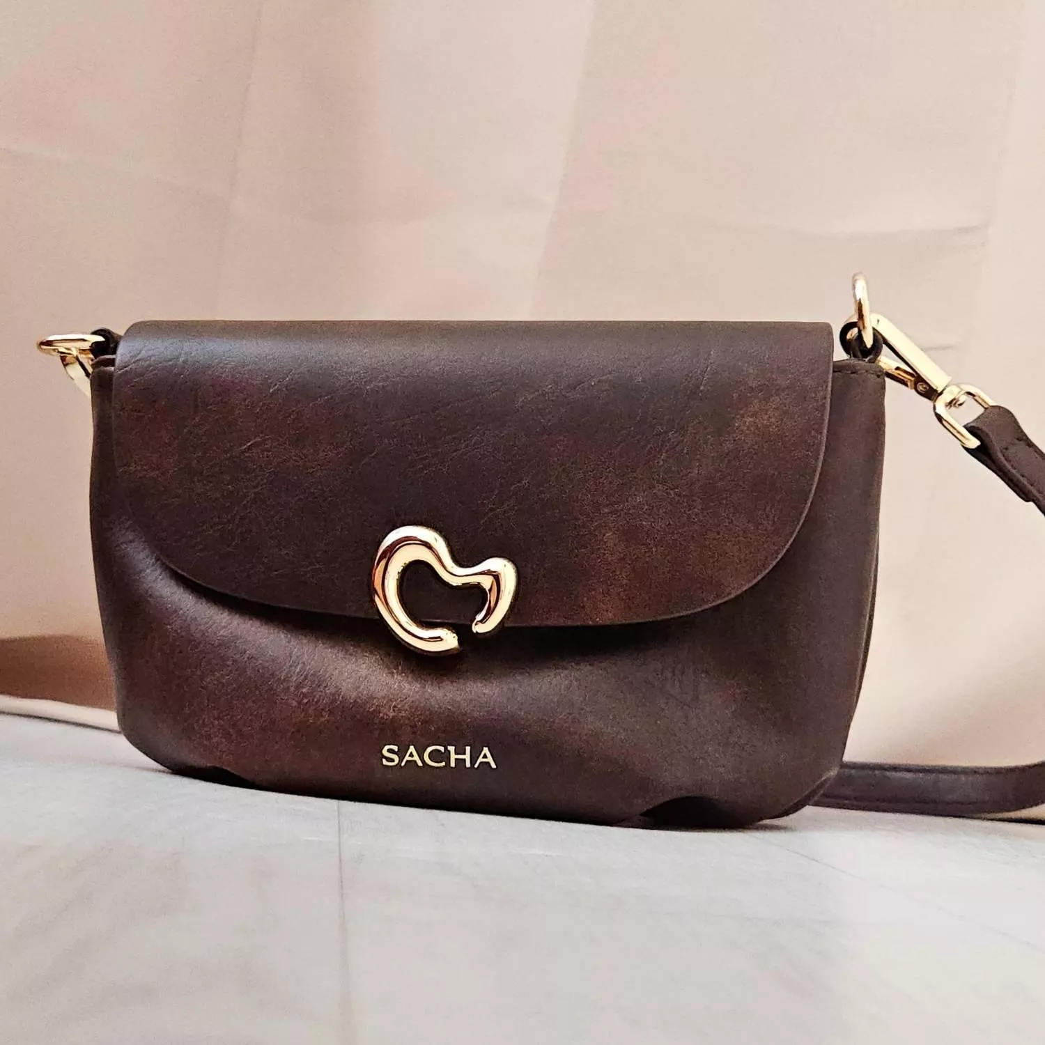 【YZGM羽之共鳴服飾《深焙可可》復古揉紋心形釦飾包】  迷人的醇厚色澤結合復古揉捻紋理 皮革表面細微的紋路變化，賦予包包一種如古董珍藏般的歲月韻味 流線型的心形金屬釦環，演繹著優雅且不羈的浪漫情懷  ✨ 商品亮點 復古皮革揉紋，每一面都獨具質感 特殊流線心鎖釦，點綴亮點細節 圓潤包身曲線，好收納隨身物品   【商品資訊】 顏色： 深咖啡色 尺寸：22 &times; 9 x 14 公分（長x寬x高） 材質：人造皮革 閉合型式 ：磁吸釦+拉鍊 製造：馬來西亞 Malaysia