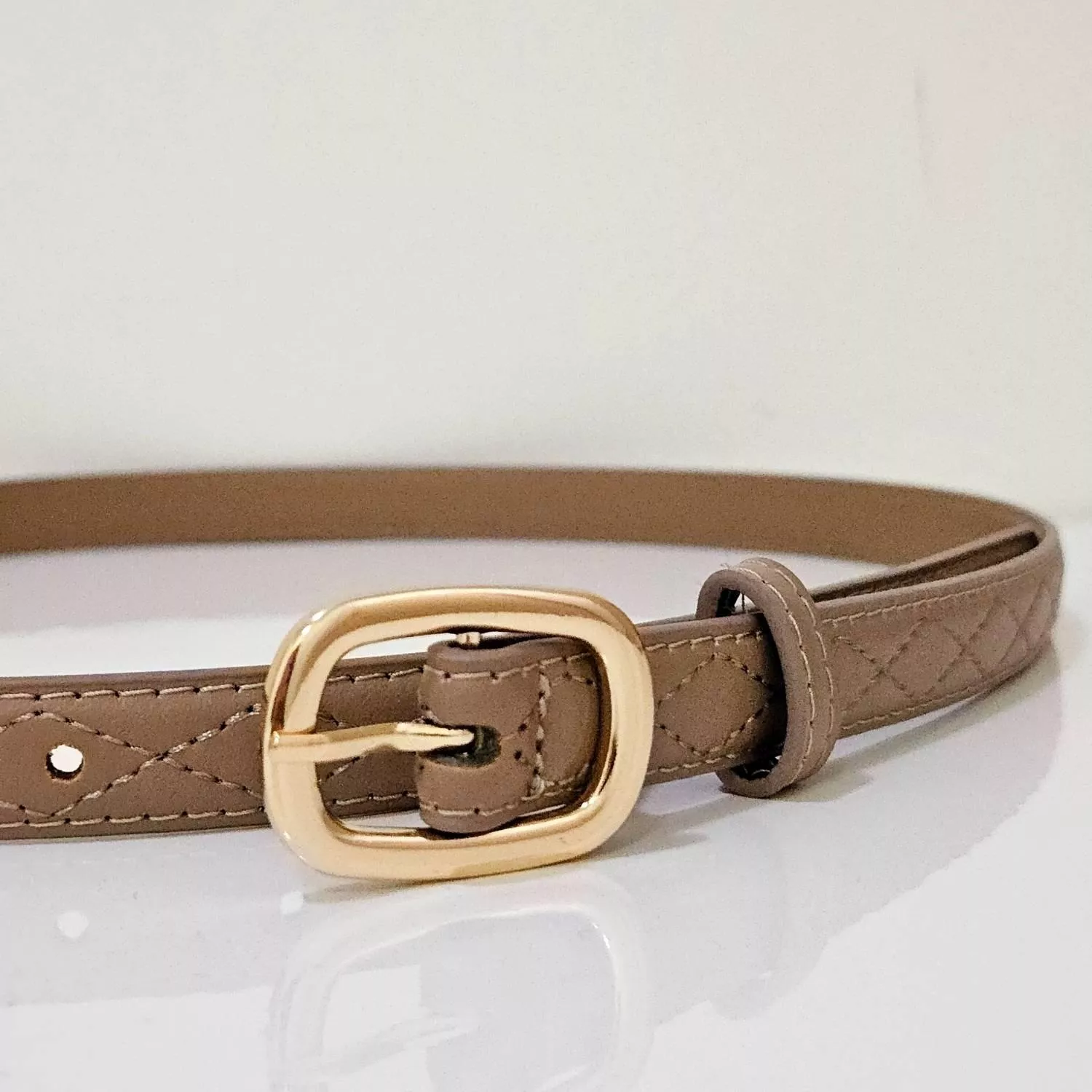 【YZGM羽之共鳴服飾《奶茶格紋》金屬圓釦菱格腰帶 (深奶茶色/淺奶茶色)】  溫潤的奶茶色調揉合優雅的菱格壓紋，在光影下呈現細膩的立體層次 精緻的金色圓釦圓潤大方，讓日常穿搭瞬間充滿精緻細節  ✨ 商品亮點 菱格壓紋工藝，質感加倍 溫柔奶茶色，與大地色系完美融合 圓潤金屬釦環，柔化腰線視覺 顯瘦度極佳的細帶設計  穿搭建議： 格紋西裝外套 / 毛呢裙 / 復古洋裝 / 法式浪漫風  【商品資訊】 顏色：深奶茶色/淺奶茶色 尺寸：106.6 x 1.8 公分（長x寬） 材質：人造皮革 製造：馬來西亞 Malaysia