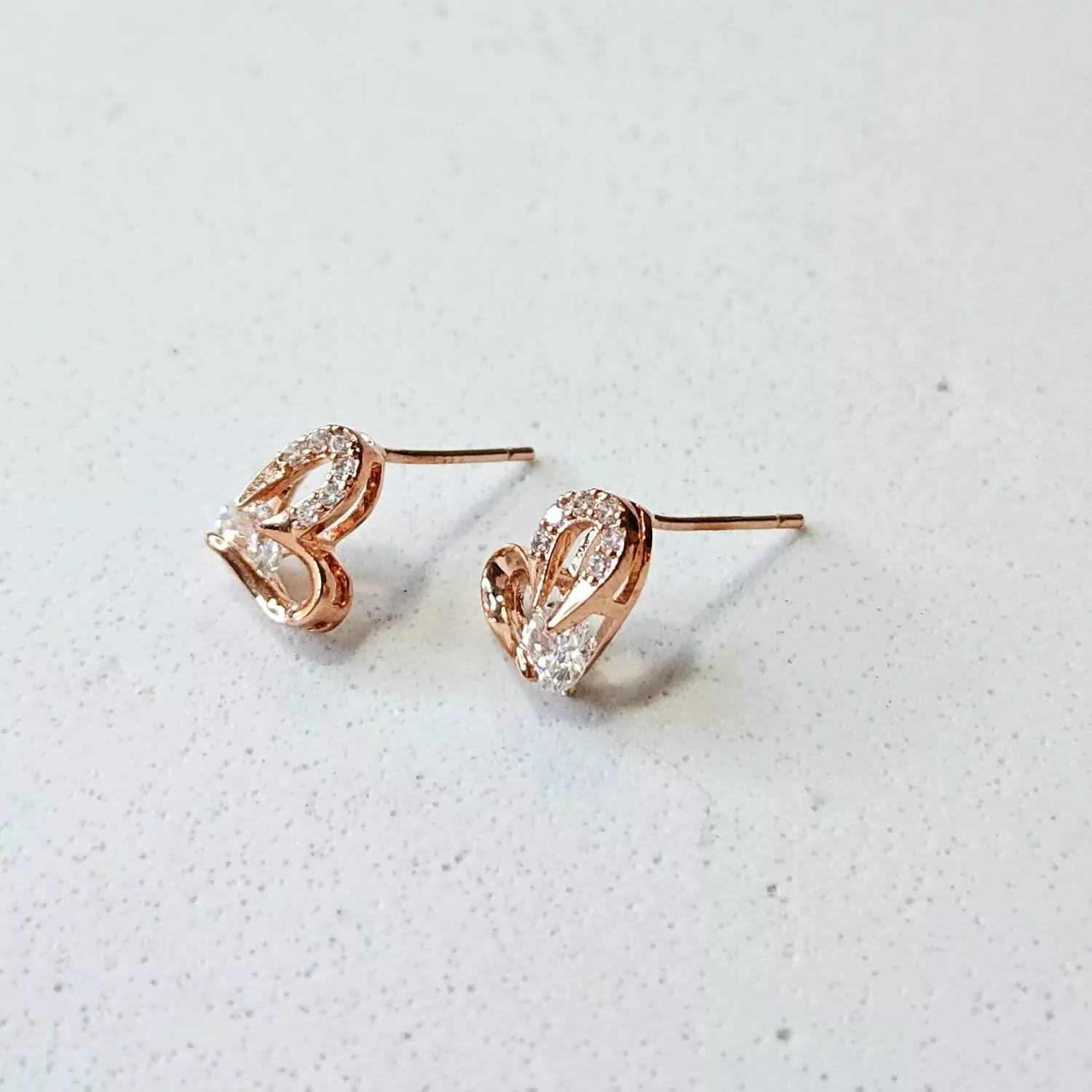 優雅的玫瑰金線條勾勒出鏤空心形， 一側鑲嵌細密的閃鑽，中心點綴一顆奪目的鋯石 簡約卻充滿力量感，演繹著輕奢的現代美學  ✨ 商品亮點 經典鏤空心形，時髦耐看 玫瑰金鍍層，襯托亞洲膚色 主石閃耀吸睛，修飾臉型 正式場合與日常約會皆適配  穿搭建議： V領襯衫 / 小黑裙 / 晚宴 / 商務餐敘 / 情人節約會  【商品資訊】 ．耳針材質 ：低敏S925銀針 ．商品材質 ：鋯石(蘇聯鑽)、厚鍍14k金 ．Size 尺寸 ：1.2 x 0.7cm ．一對販售
