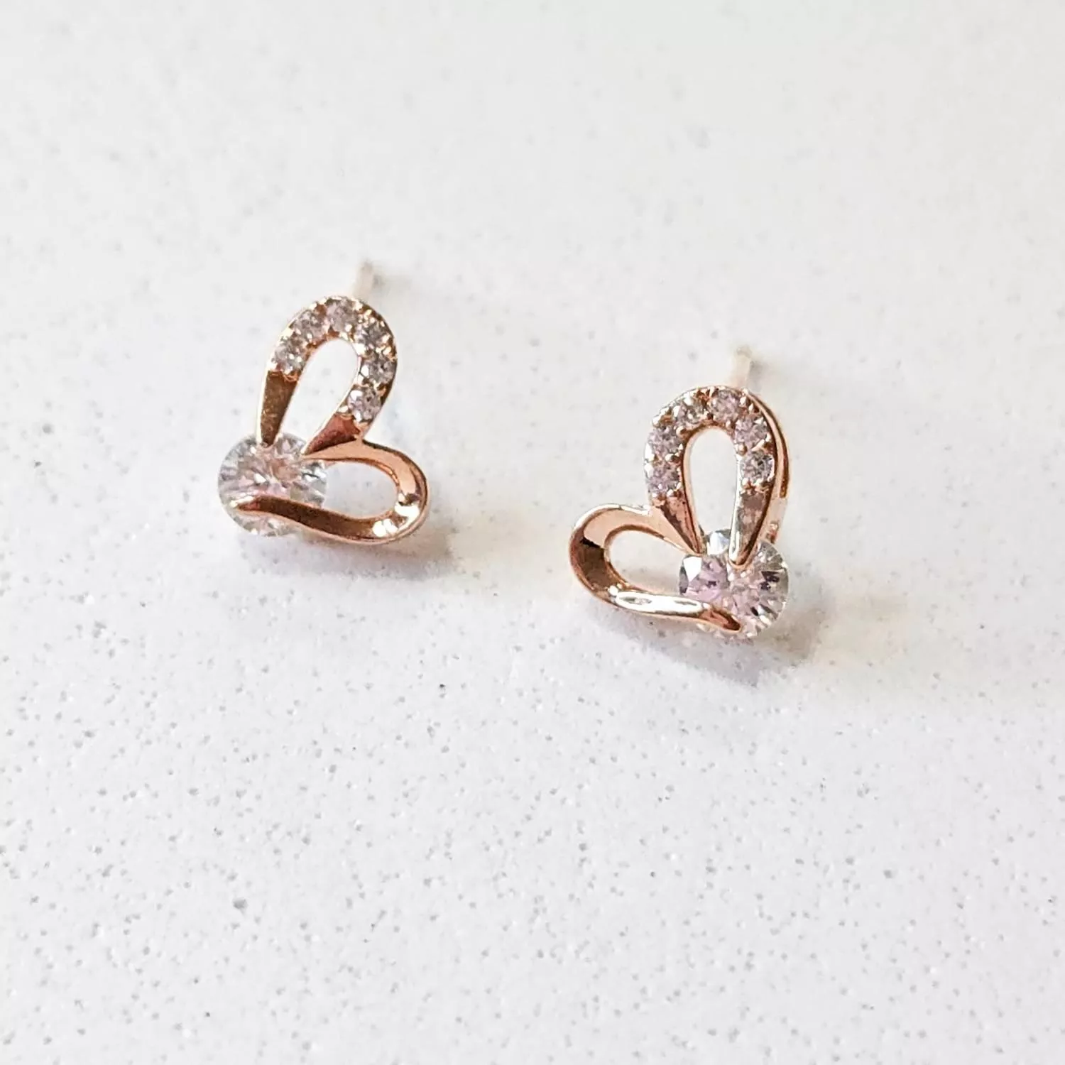 優雅的玫瑰金線條勾勒出鏤空心形， 一側鑲嵌細密的閃鑽，中心點綴一顆奪目的鋯石 簡約卻充滿力量感，演繹著輕奢的現代美學  ✨ 商品亮點 經典鏤空心形，時髦耐看 玫瑰金鍍層，襯托亞洲膚色 主石閃耀吸睛，修飾臉型 正式場合與日常約會皆適配  穿搭建議： V領襯衫 / 小黑裙 / 晚宴 / 商務餐敘 / 情人節約會  【商品資訊】 ．耳針材質 ：低敏S925銀針 ．商品材質 ：鋯石(蘇聯鑽)、厚鍍14k金 ．Size 尺寸 ：1.2 x 0.7cm ．一對販售
