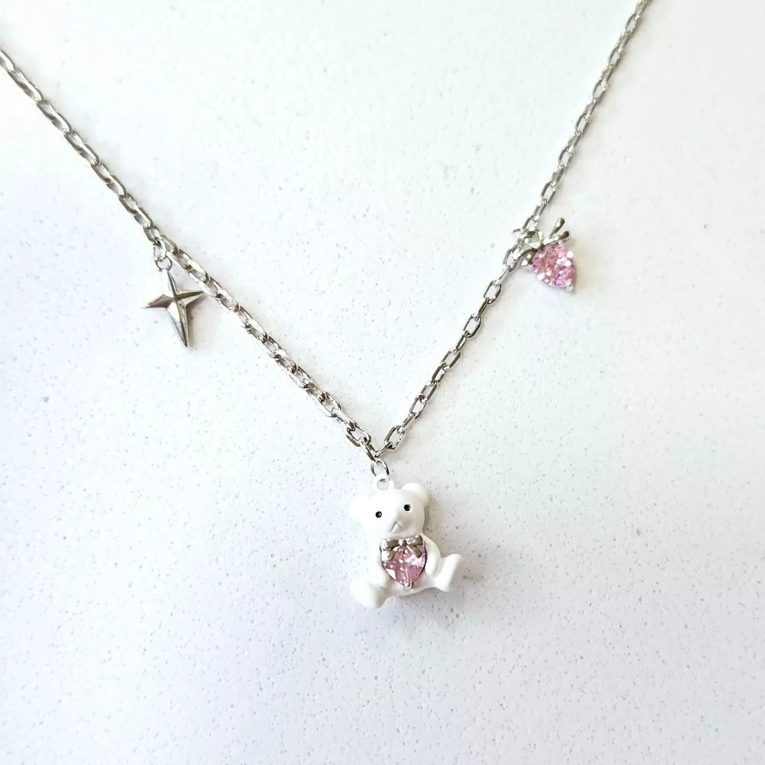 潔白瑩潤的小熊懷抱著一顆粉色璀璨愛心 像是守護著心底最純真的夢想 細緻的銀色鍊條搭配點綴的星芒與墜飾 在頸間閃耀著動人的純真光芒  ✨ 商品亮點 立體小熊造型，俏皮可愛 粉色心形主石，閃耀立體光澤 精緻吊墜裝飾，層次豐富 抗氧化電鍍，佩戴舒適  穿搭建議： 圓領T恤 / 甜美洋裝 / 針織衫 / 閨蜜穿搭 / 慶生約會  【商品資訊】 ．鍊條材質 ：低敏S925銀 ．商品材質 ：鋯石(蘇聯鑽) ．Size 尺寸 ：56 cm (外加延長鏈4cm)