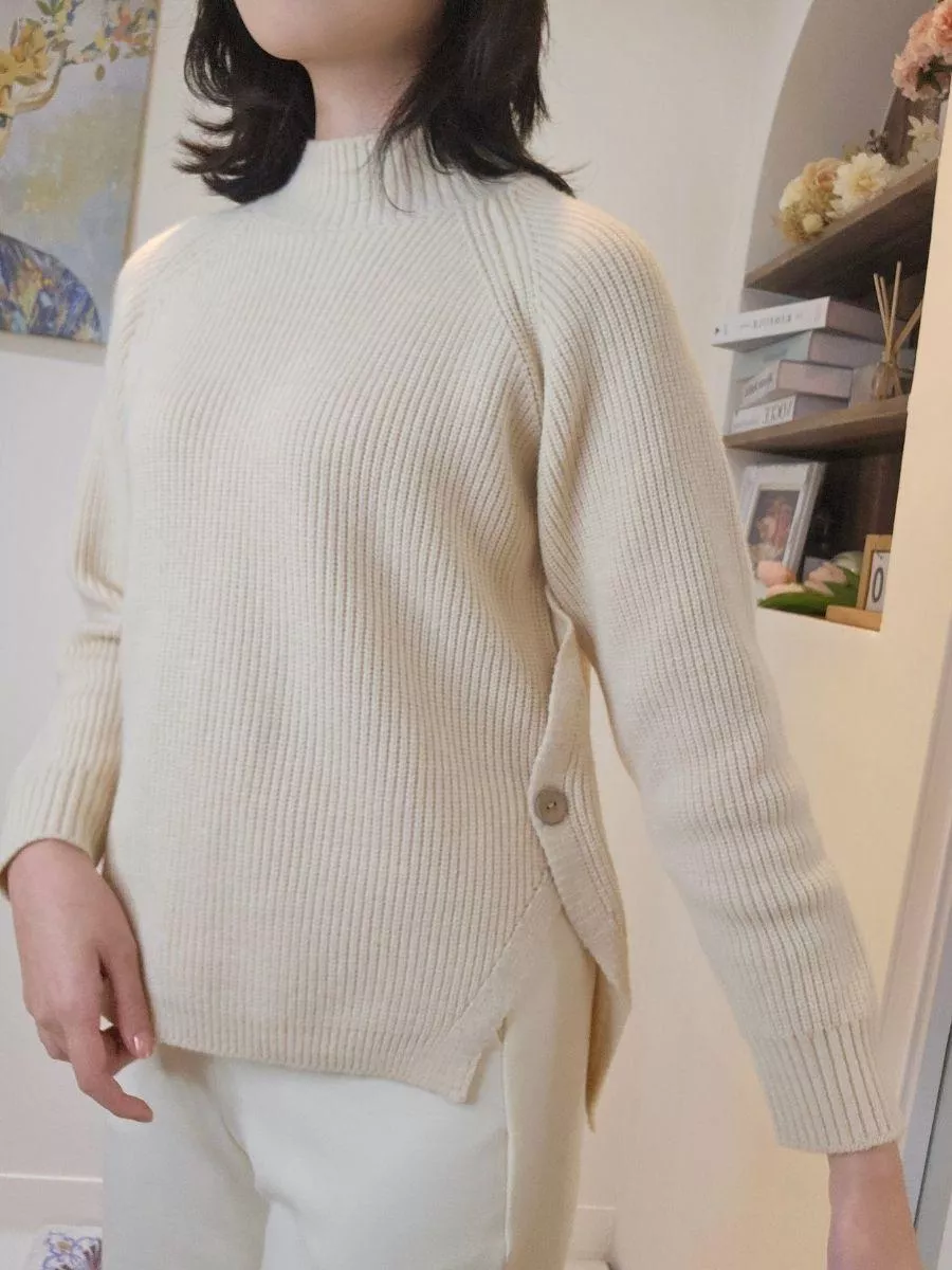 《霧色詩篇》側開叉木鈕扣高領針織上衣 &mdash;&mdash; 如晨霧般輕柔，將慵懶與詩意穿在身上。 &mdash;&mdash;  【設計細節：低調而不平庸】 側擺處加入了細膩的開叉設計與質感木鈕扣，打破了傳統針織衫的沉悶感。 側邊的線條延伸能巧妙地修飾腰臀曲線，無論是自然垂墜或是將前襬紮入長裙，都能呈現極具層次感的視覺效果。  【產品亮點】 溫潤色澤： 奶油般的霧白色調，襯托亞洲女孩的膚色，讓妳在冷色調的冬日裡自帶溫柔光圈。 黃金比例高領： 恰到好處的立領高度，保暖卻不勒脖，完美修飾頸部線條。 微寬鬆修飾剪裁： 慵懶的廓形設計，藏起腰間肉肉，給妳最自在的包裹感。 細膩坑條織紋： 垂直的立體坑條織法，在視覺上達到收縮效果，穿上即顯瘦。  【穿搭靈感】 同色系高級感： 搭配白色西裝褲或針織裙，利用不同層次的白營造簡約高級的視覺美。 文藝休閒風： 下身換上牛仔褲與短靴，將開叉處的鈕扣微微露出，展現不經意的隨興美感。