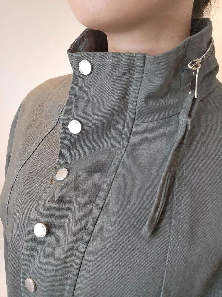 《灰影旅途》工裝立領短版夾克外套 &mdash;&mdash; 在城市的喧囂中，展開一場隨興而自由的風格冒險。 &mdash;&mdash;  【設計細節：剛柔並濟的靈魂】 =克將經典的工裝元素與現代短版廓形完美結合。 沈穩的軍綠色調（灰影綠）自帶一種不費力的時髦感，搭配領口與前襟精緻的金屬圓扣設計，在帥氣之中注入了細膩的質感。 不論是隨意敞開領口，或是全扣後的立領穿法，都能展現不同的層次張力。  【產品亮點】 黃金比例短版剪裁：短版設計，能視覺上拉高腰線，比例更顯挑高。 舒適落肩闊型： 不挑身形，消除了肩膀的沈重感，內搭厚實針織衫也依然俐落。 機能質感面料： 採用具挺度的布料，穿上即顯挺括有神，不易皺好打理，是旅途中最可靠的穿搭夥伴。  【穿搭靈感】 個性混搭： 內搭柔美的針織毛衣，運用針織與工裝布料的「剛柔對比」，層次感十足。 街頭運動： 搭配高腰寬褲與白布鞋，輕鬆穿出帥氣又顯腿長的街頭時髦。