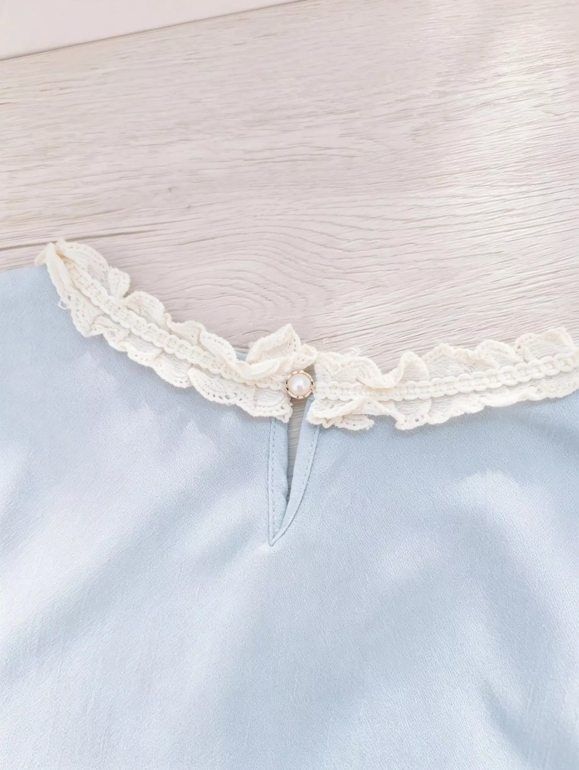 Light blue round neck short sleeve chiffon blouse with delicate lace collar detail.