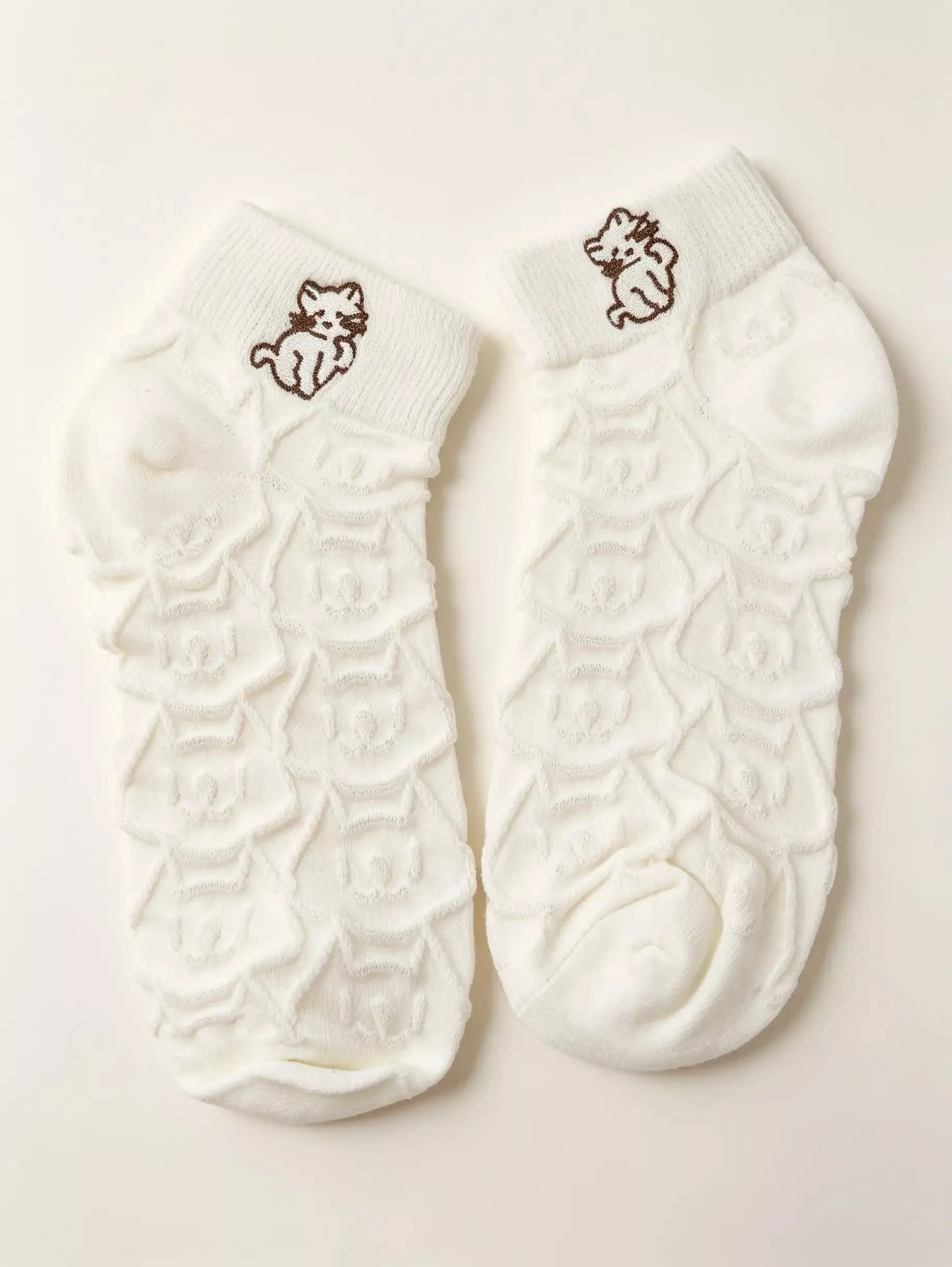 一雙白色貓咪刺繡針織中筒襪平放展示，整體造型簡約且帶有半糖甜美感。