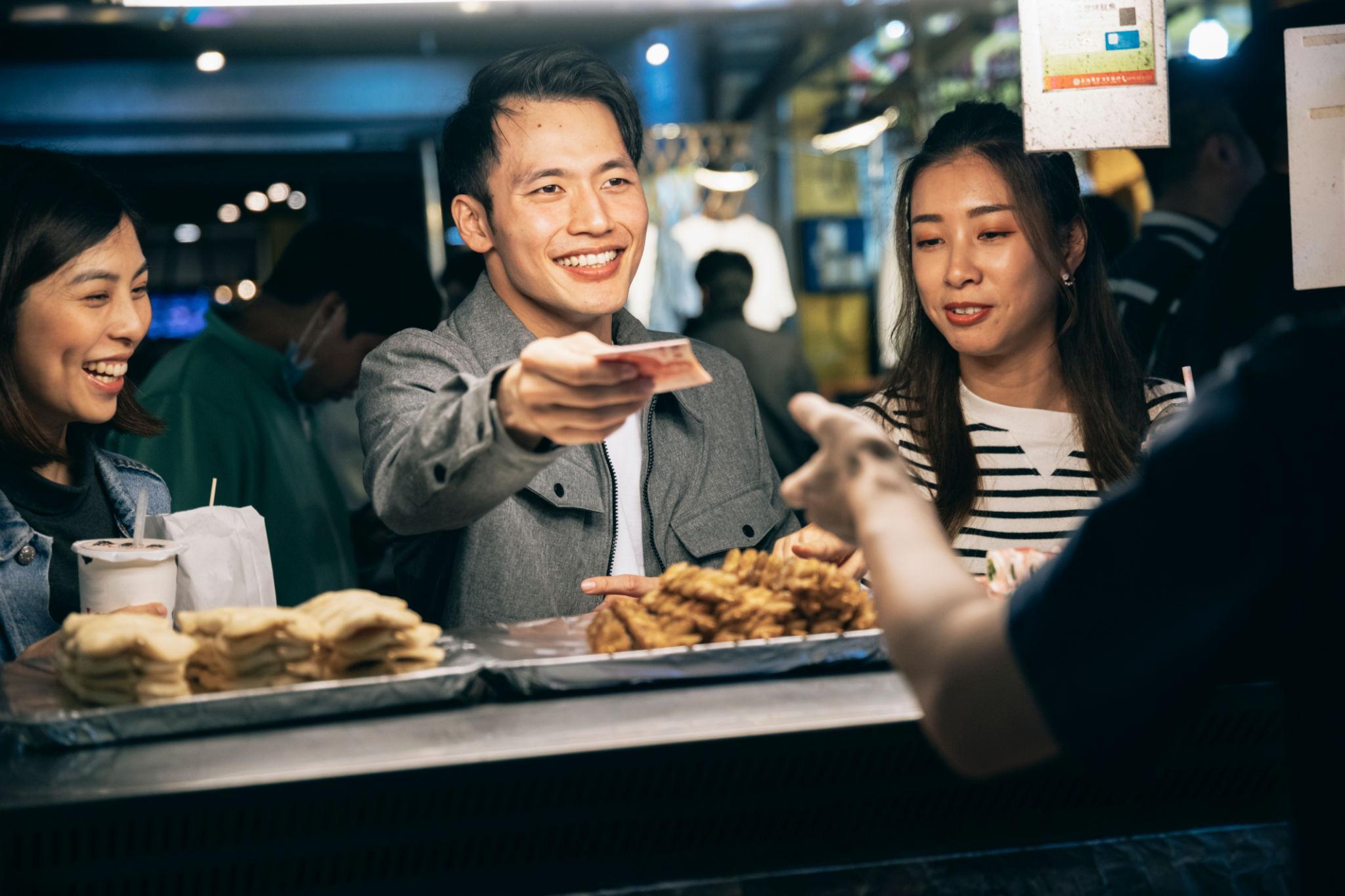 Visitors walking between food stalls at a Taiwan night market