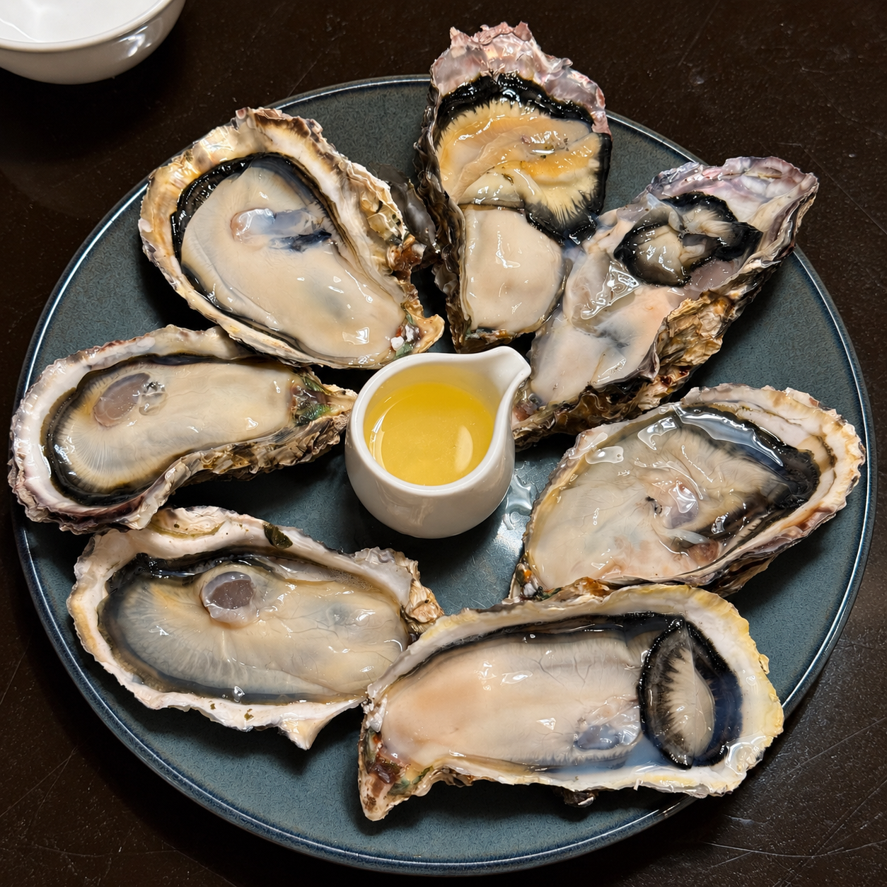 生蠔怎麼吃最對味?室津生蠔搭配醬汁,享受海鮮美味 日本兵庫室津生蠔料理,數顆帶殼生蠔整齊擺放於深藍色圓盤,搭配黃色醬汁,呈現飽滿蠔肉與精緻擺盤。